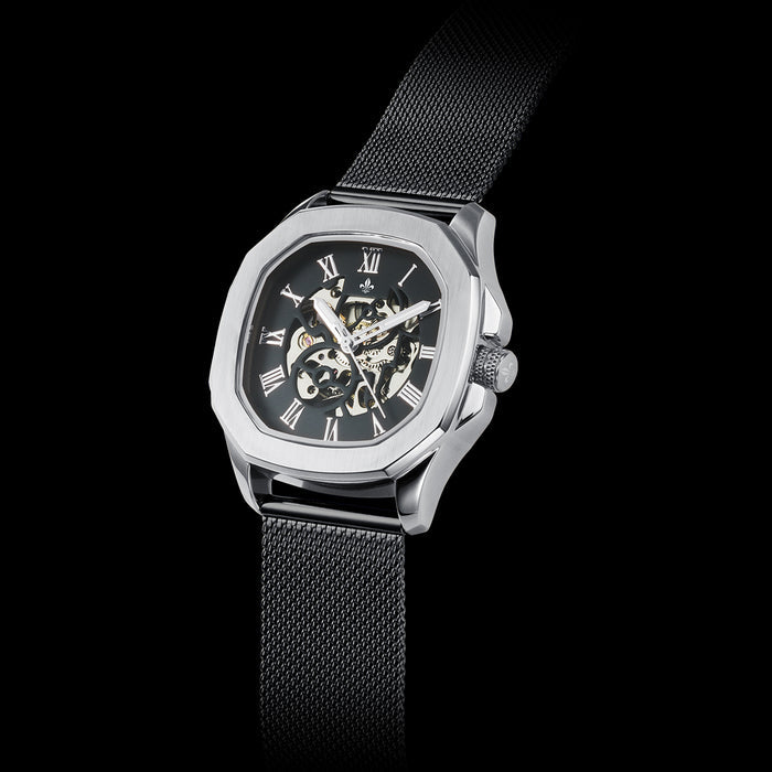 Luxury men's watch with a black dial featuring Roman numerals, visible intricate watch mechanics, and a black mesh interchangeable strap, bold by design.