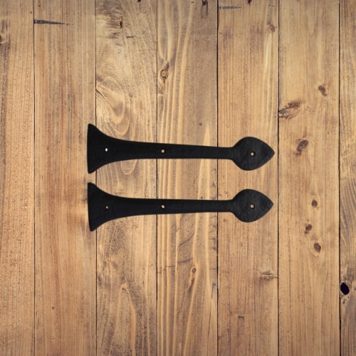 Two black, flat metal shelf brackets by Prima Decorative Hardware, shaped like arrows, are placed parallel on a light wooden surface and feature a durable black powder coated finish for added style.