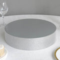 Silver cake stand with a mirrored top and textured base.