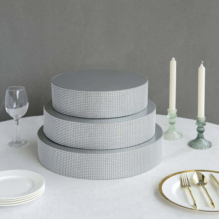 Three-tiered gray cake drum set with rhinestone embellishments on a table.